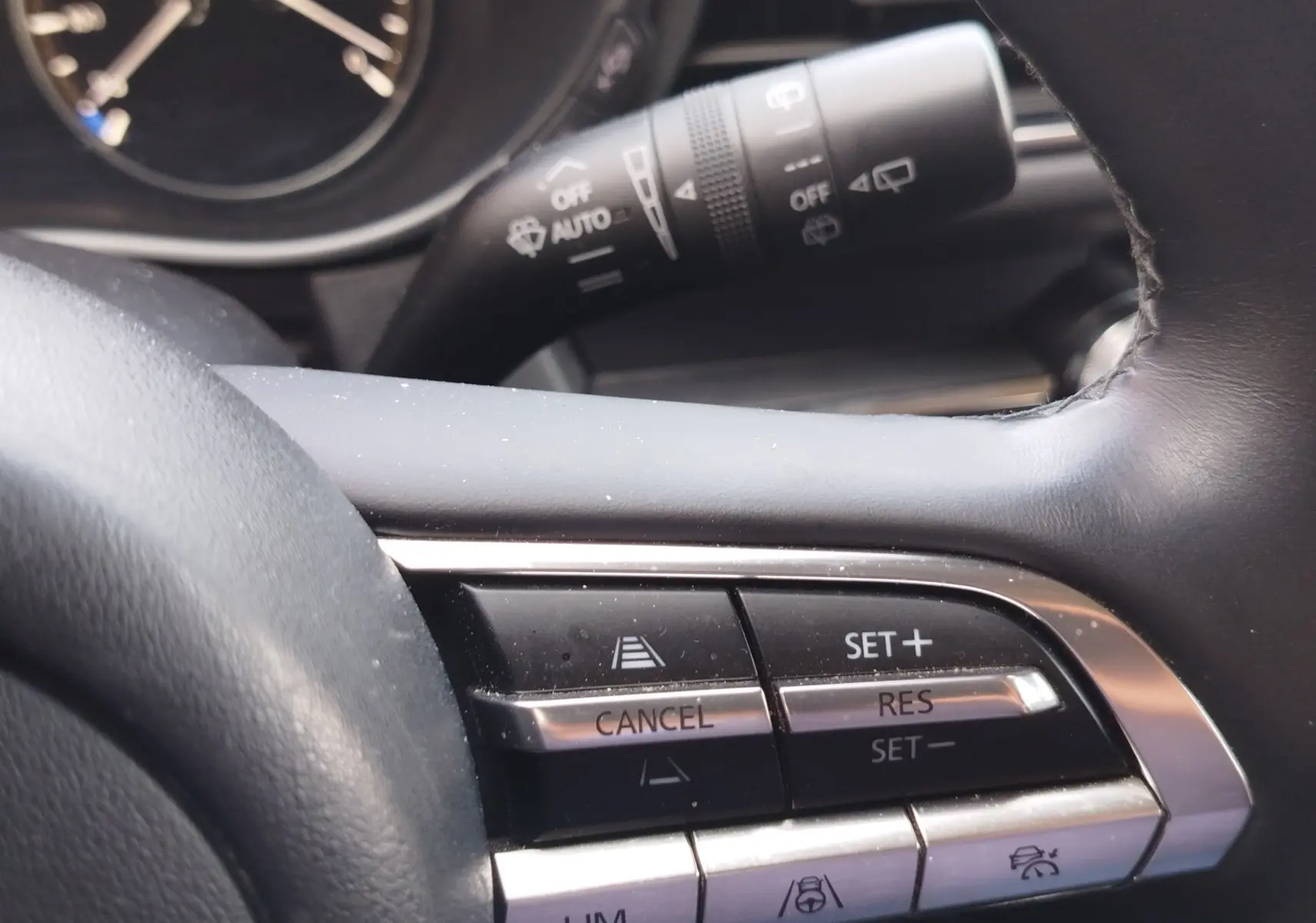 Gros plan sur les commandes au volant du Mazda CX-30 2020, mettant en valeur les boutons de régulateur de vitesse.