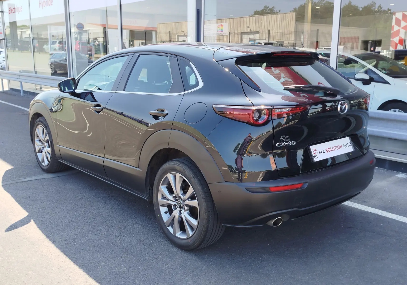 Vue 3/4 arrière droite d'un Mazda CX-30 noir 2020 avec feux arrière ronds et jantes alliage 18 pouces.