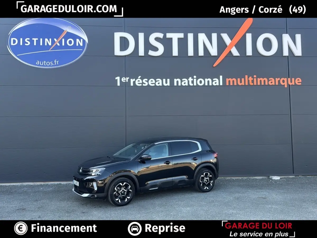 Vue de profil côté gauche d'un Citroën C5 Aircross noir 2025 stationné devant un mur gris avec logo Distinxion.