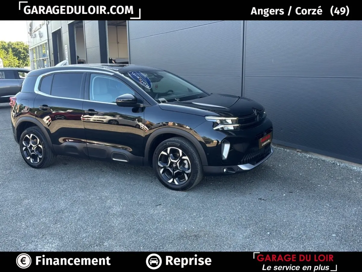 Vue 3/4 avant droit d'un SUV Citroën C5 Aircross noir brillant garé devant un mur gris.