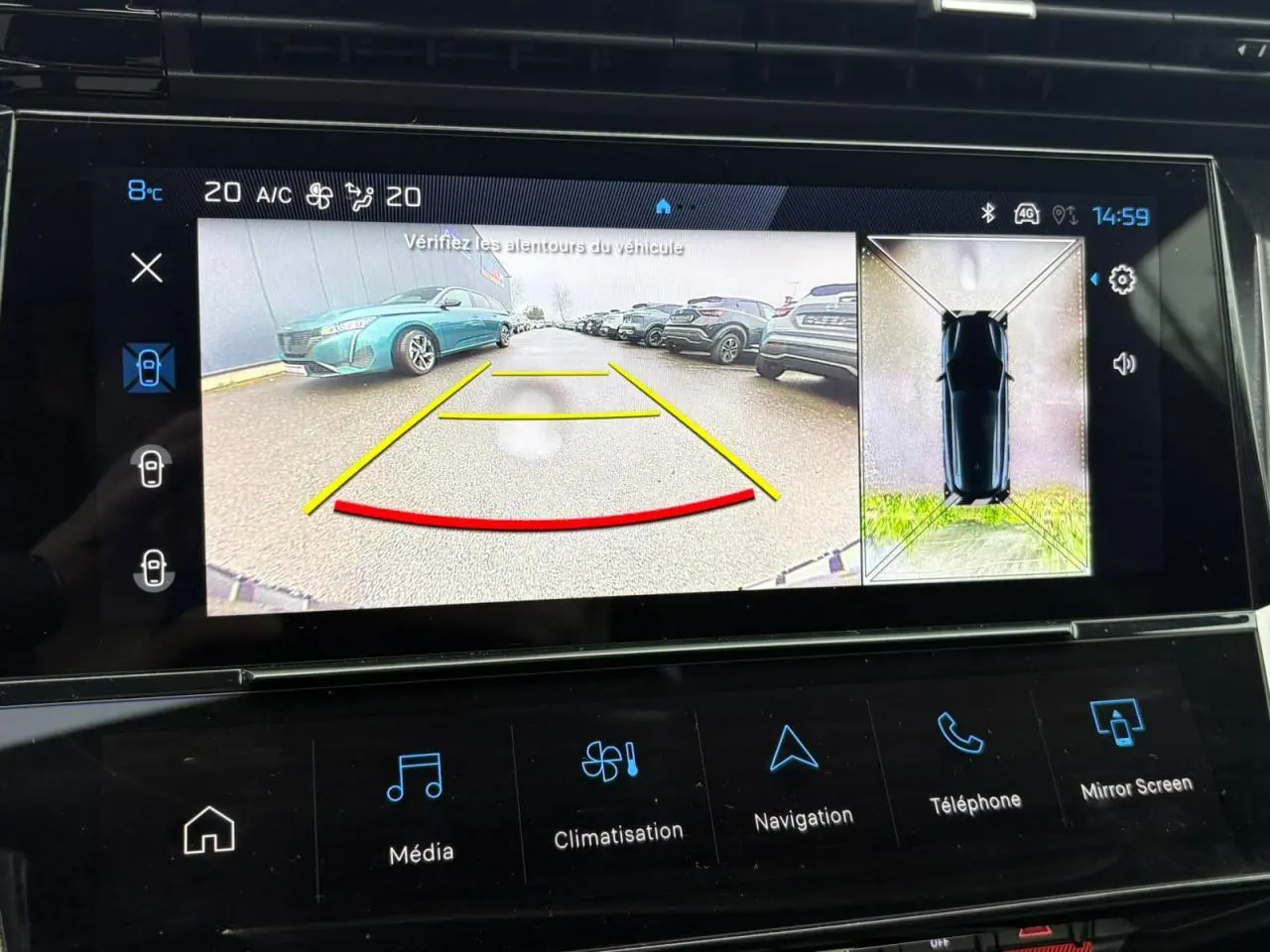 Écran tactile montrant la caméra 360° avec vue arrière et vue aérienne d’une Peugeot 308 SW gris Artense.