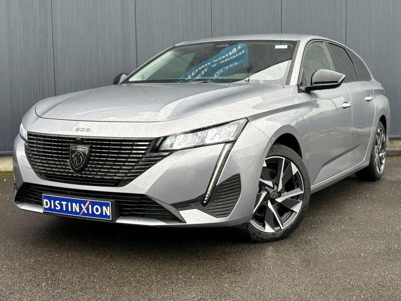 Peugeot 308 SW Hybrid gris Artense vue 3/4 avant droit avec calandre noire et jantes alliage 17 pouces.