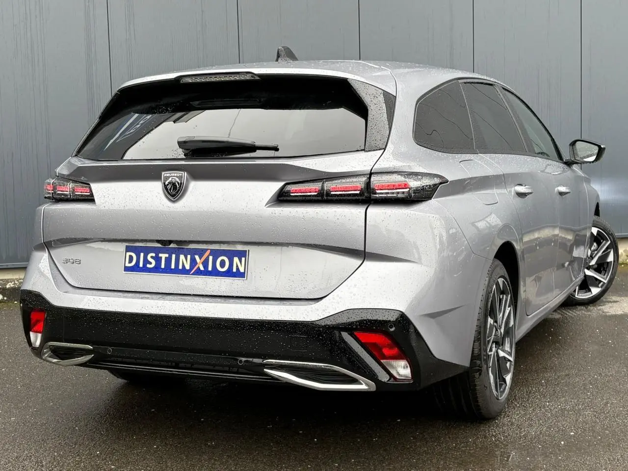 Vue 3/4 arrière droite d'une Peugeot 308 SW Hybrid gris Artense avec feux LED et jantes alliage 17 pouces.