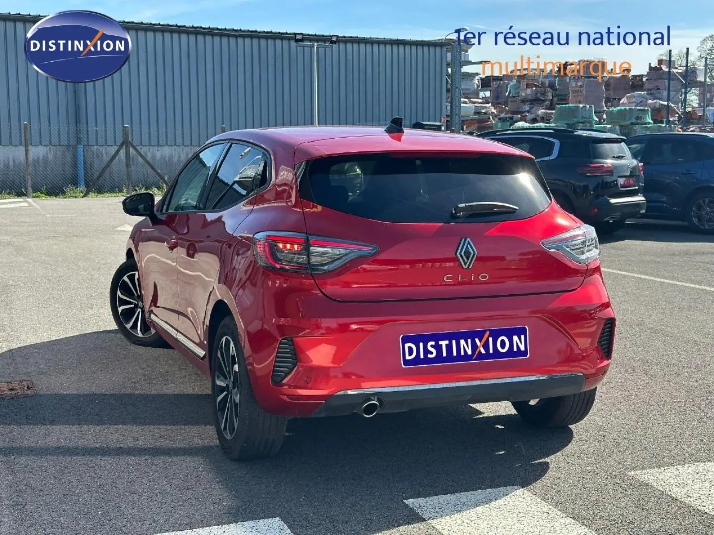 Vue 3/4 arrière droite d'une Renault Clio rouge flamme avec feux arrière LED et jantes alu.