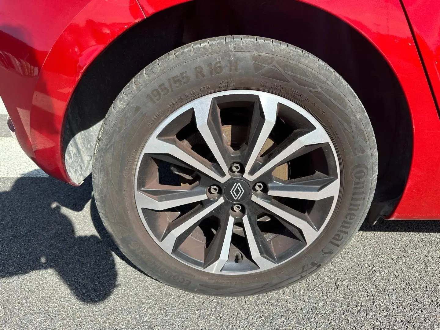 Gros plan sur la roue avant gauche d’une Renault Clio Rouge Flamme avec jante alu au design moderne.