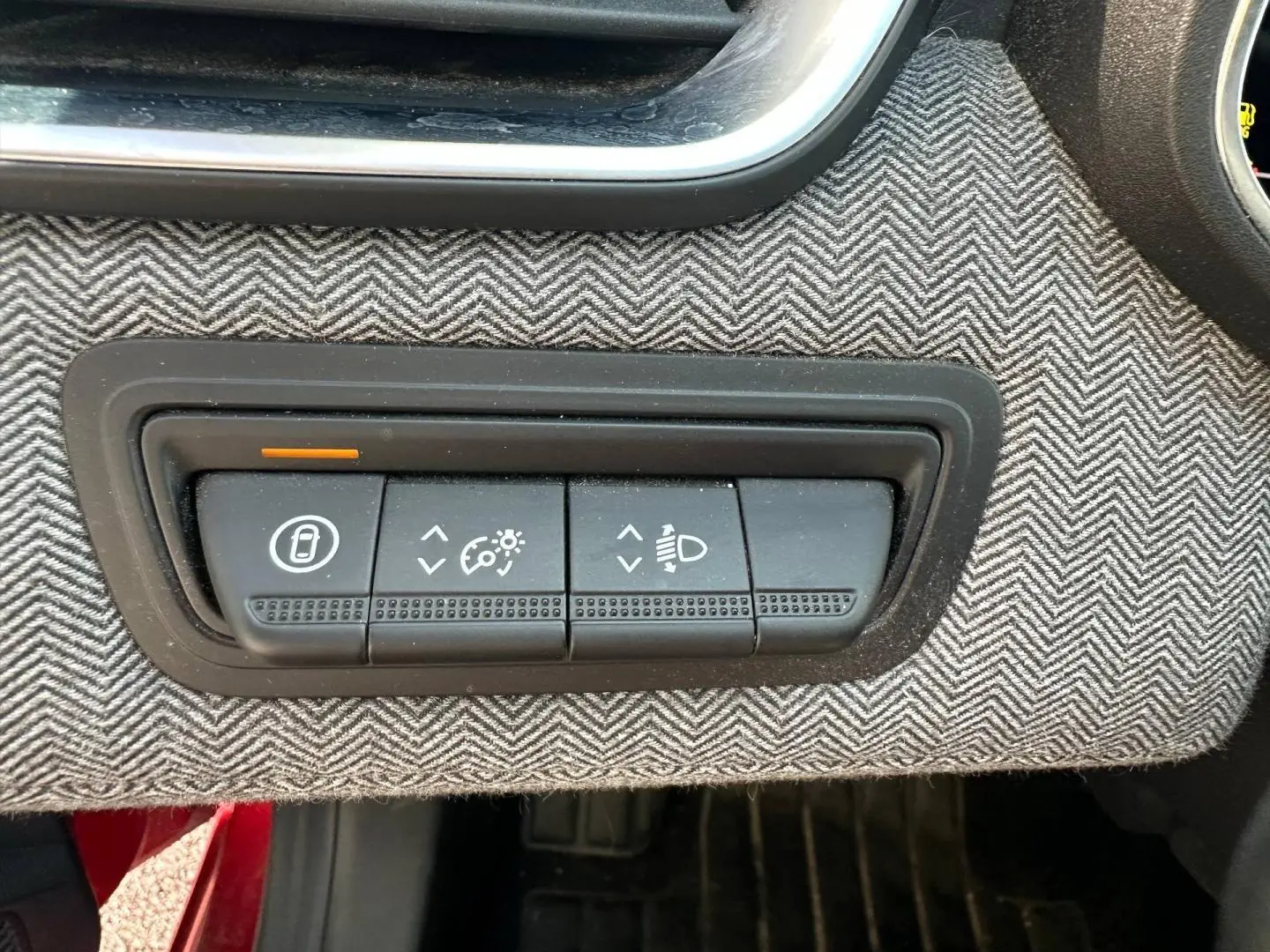 Panneau de commandes noires sur tissu gris à chevrons dans Renault Clio Rouge Flamme, réglages éclairage et verrouillage portes.