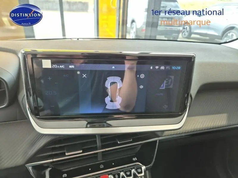 Écran tactile central affichant l'aide au stationnement dans l'habitacle d'une Peugeot 208 gris Artense.