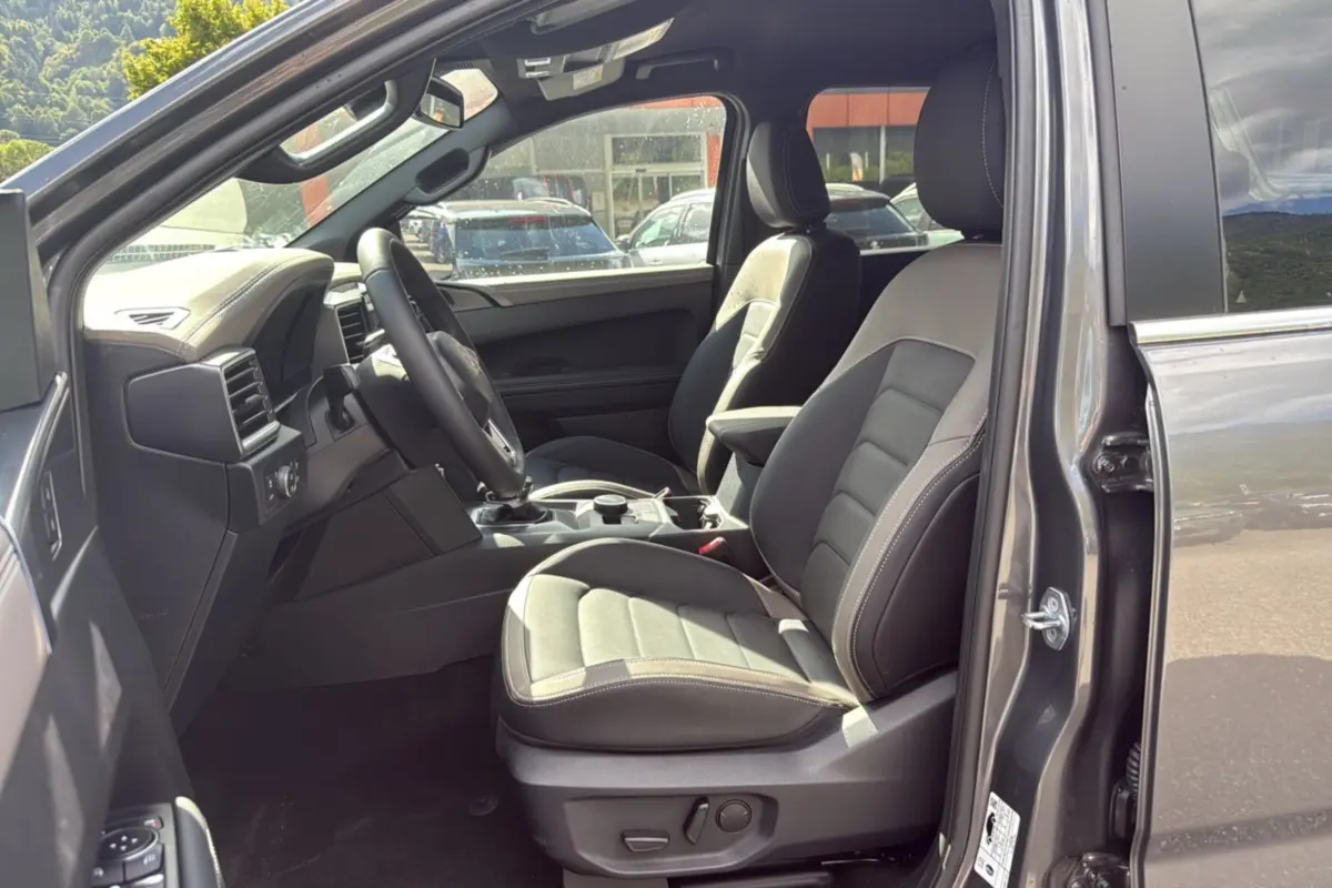 Vue intérieure côté conducteur du Volkswagen Amarok Simple Cabine gris foncé avec sièges cuir et volant multifonctions.