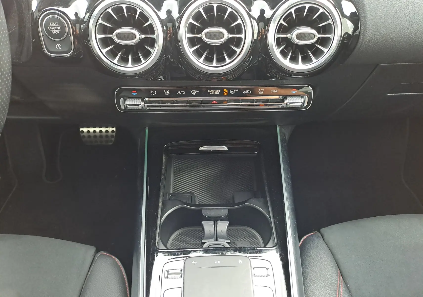 Vue rapprochée de la console centrale noire brillante et des aérateurs ronds du tableau de bord d'une Mercedes Classe B AMG Line 2019.