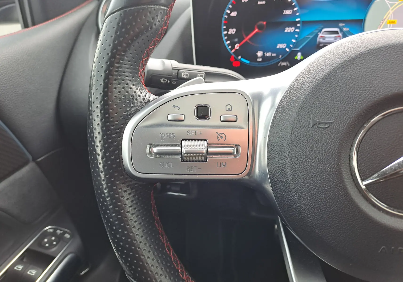 Gros plan sur le volant cuir noir perforé avec surpiqûres rouges et commandes multifonctions à gauche du Mercedes Classe B gris foncé AMG Line 2019.