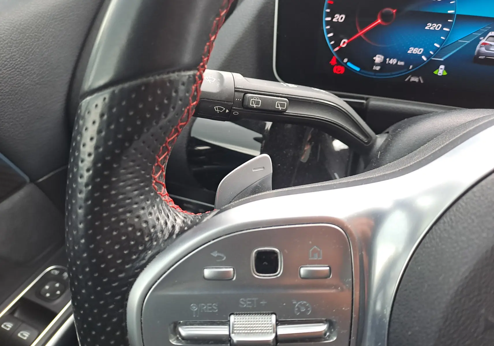 Gros plan sur le volant perforé noir avec surpiqûres rouges et commandes argentées d'une Mercedes Classe B AMG Line 2019.