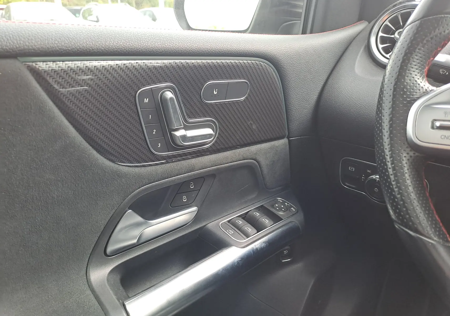 Détail de la porte côté gauche d'une Mercedes Classe B 2019 AMG Line, avec commandes de siège et finition carbone noire.