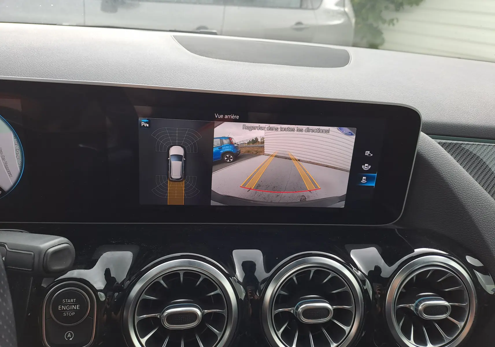 Tableau de bord de Mercedes Classe B 2019 avec écran affichant la caméra de recul et les aérateurs ronds chromés.