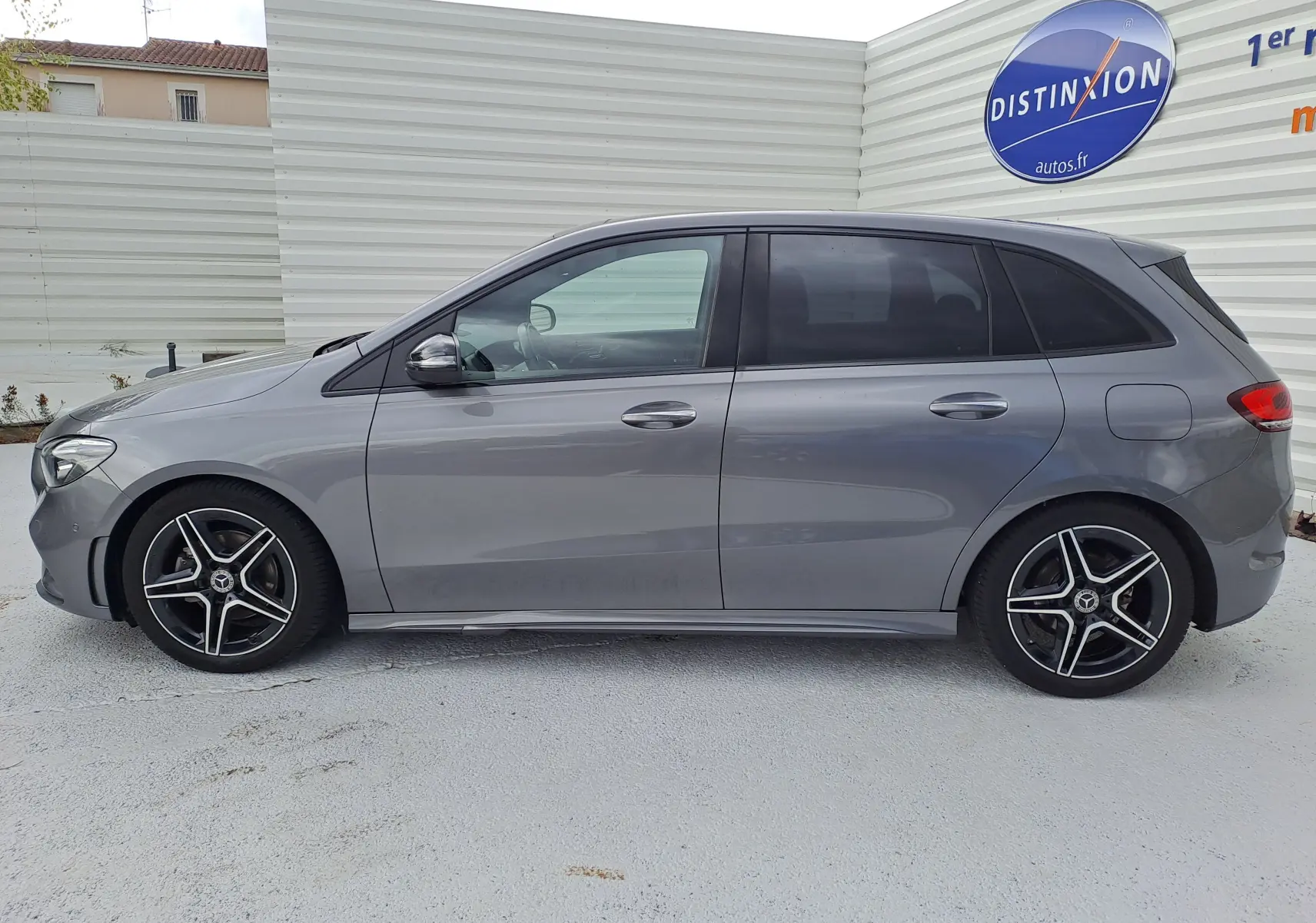 Profil côté gauche d'une Mercedes Classe B 1.3i AMG Line gris foncé métal avec jantes alliage noires et teintées.