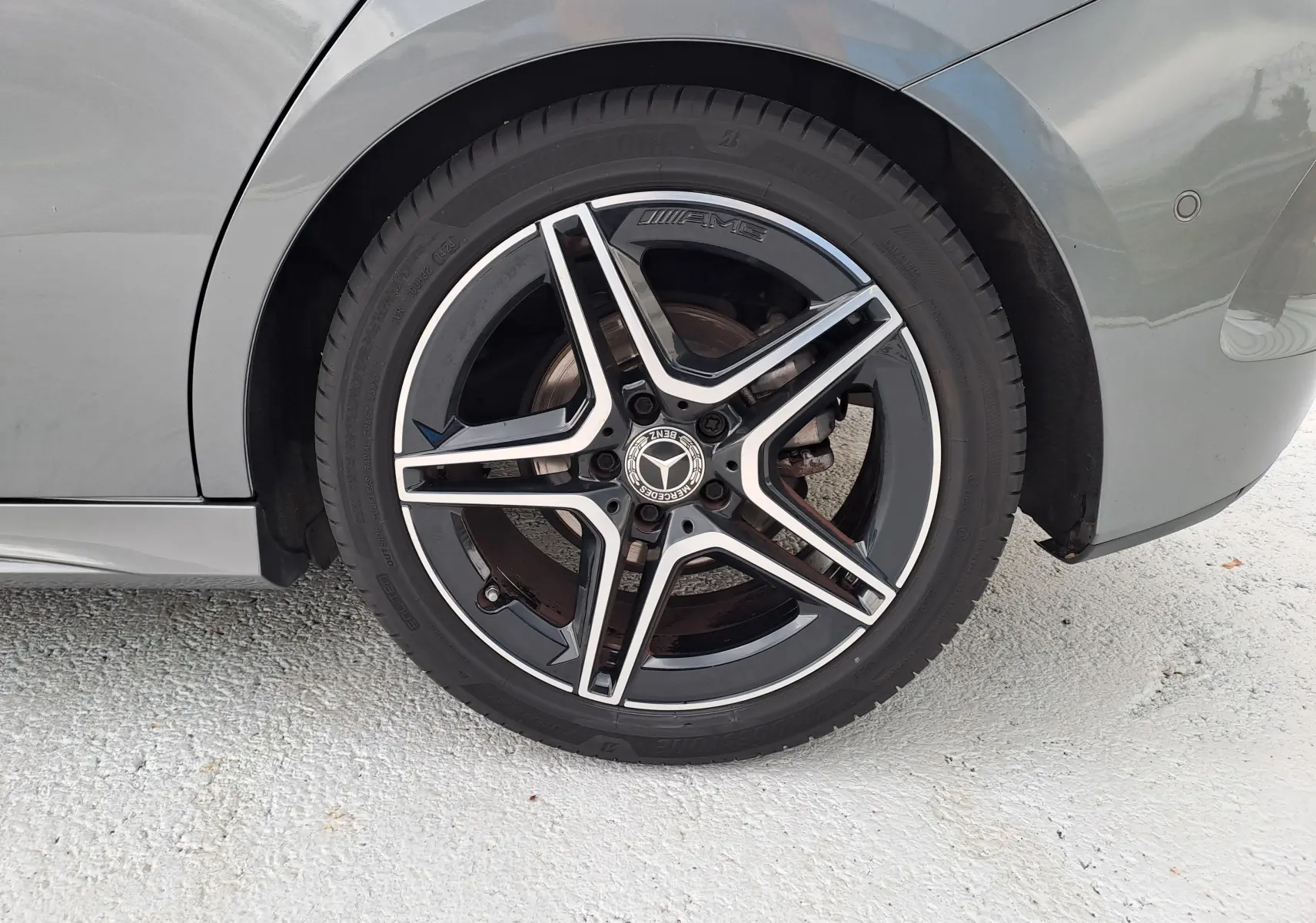 Gros plan sur la roue arrière droite gris foncé métal d'une Mercedes Classe B AMG Line avec jante AMG à cinq branches.