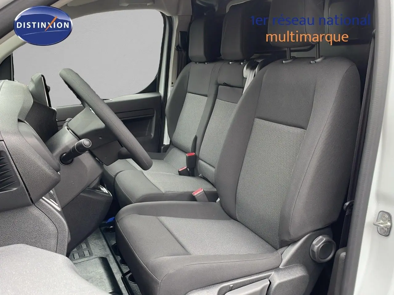 Vue intérieure côté conducteur du Peugeot Expert Fourgon blanc 2025, montrant les sièges gris et le volant simple.