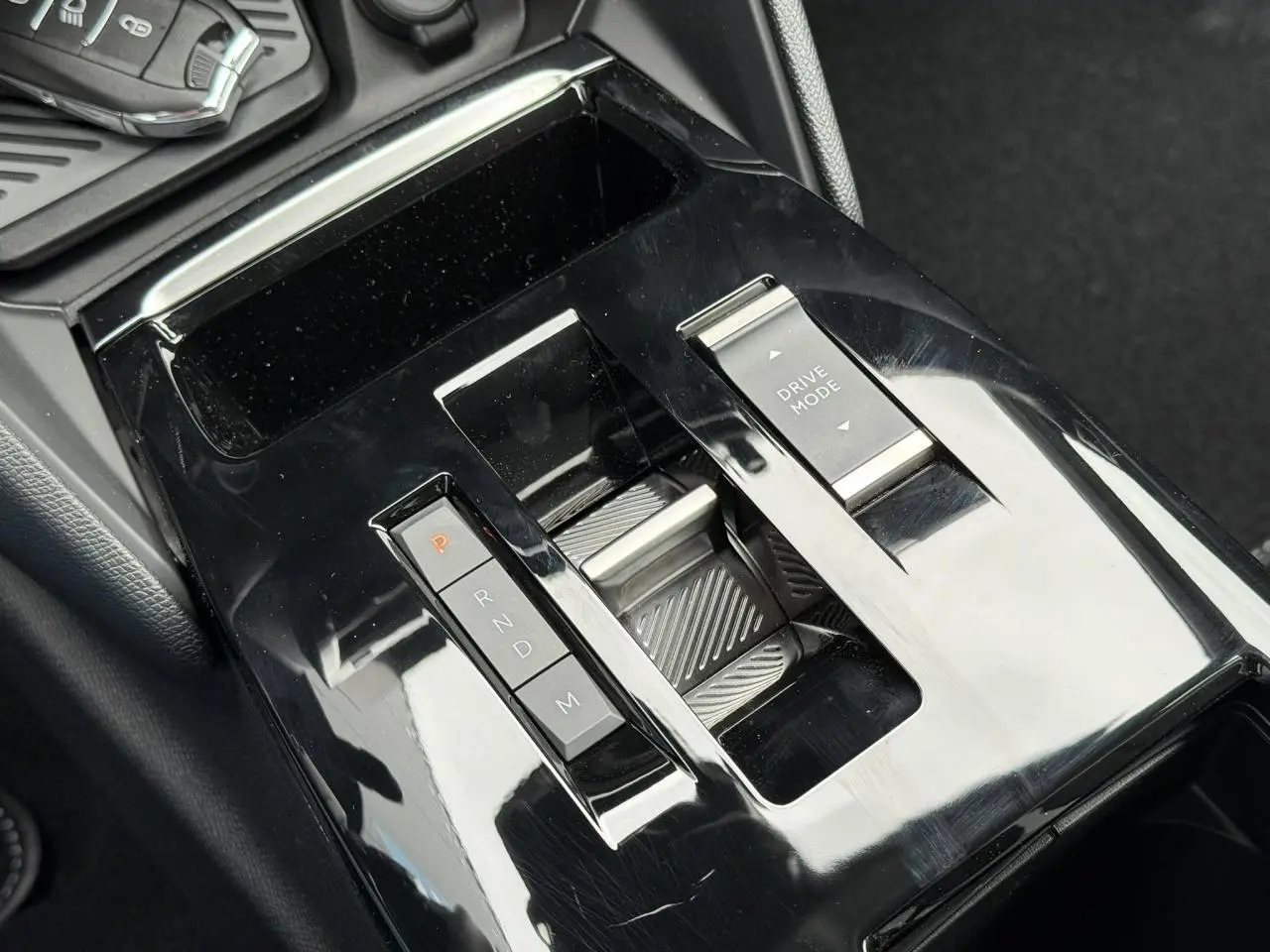 Gros plan sur la console centrale noire brillante de la Citroën C4 NV Hybrid 2025 avec commandes de boîte auto et mode de conduite.