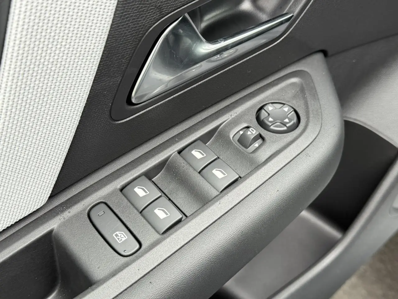 Gros plan sur les commandes de lève-vitres et réglage des rétroviseurs côté conducteur d'une Citroën C4 2025.