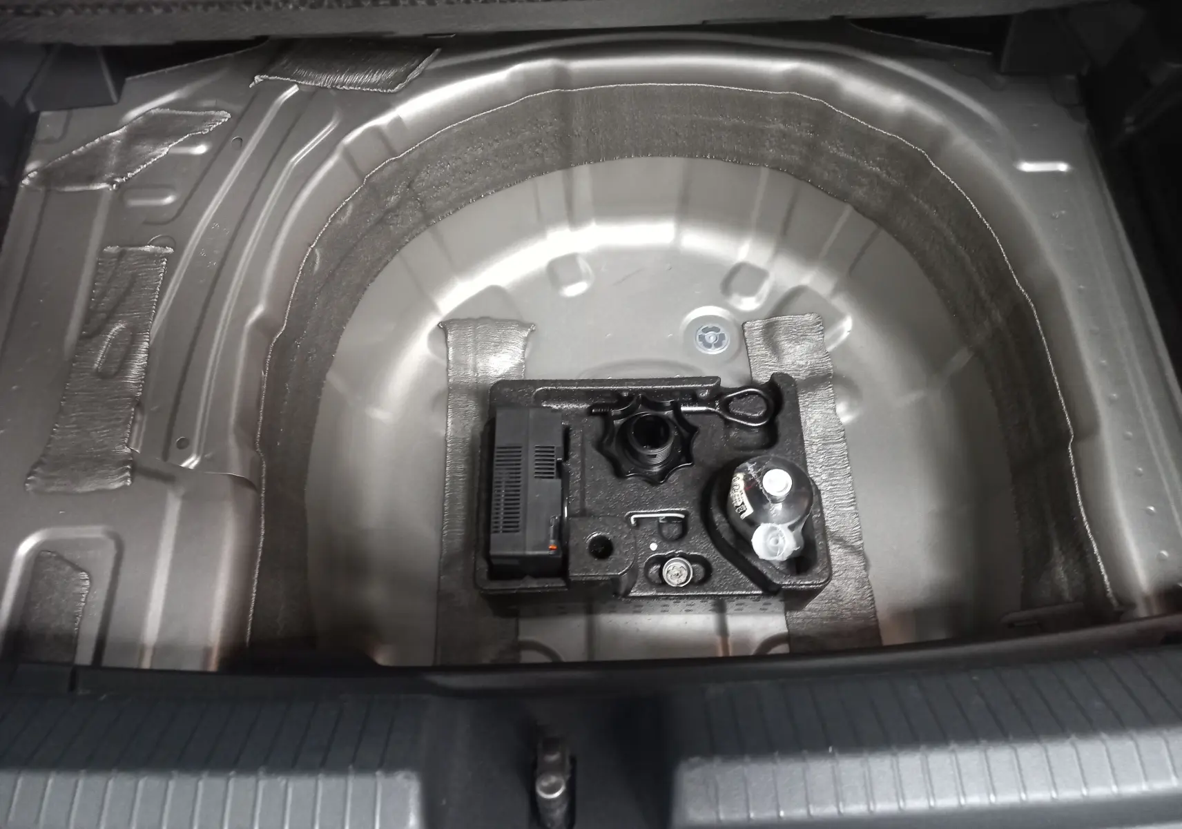 Coffre ouvert d'une Volkswagen Polo argentée 2024, montrant le rangement sous plancher sans roue de secours.