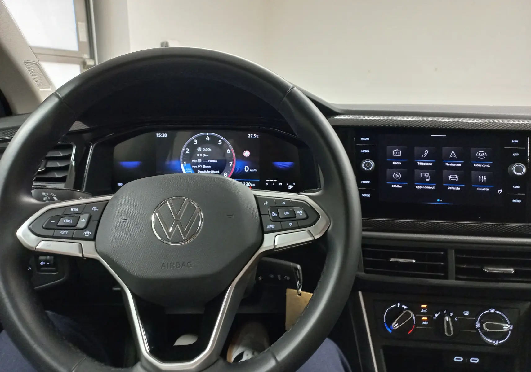 Vue intérieure du volant et du tableau de bord numérique d'une Volkswagen Polo 2024 avec écran tactile et commandes au volant.