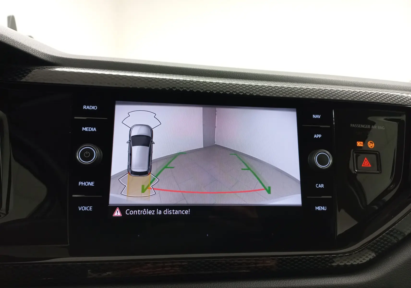 Écran de caméra de recul affichant une Volkswagen Polo 2024 argent en vue aérienne arrière avec guidage de trajectoire.