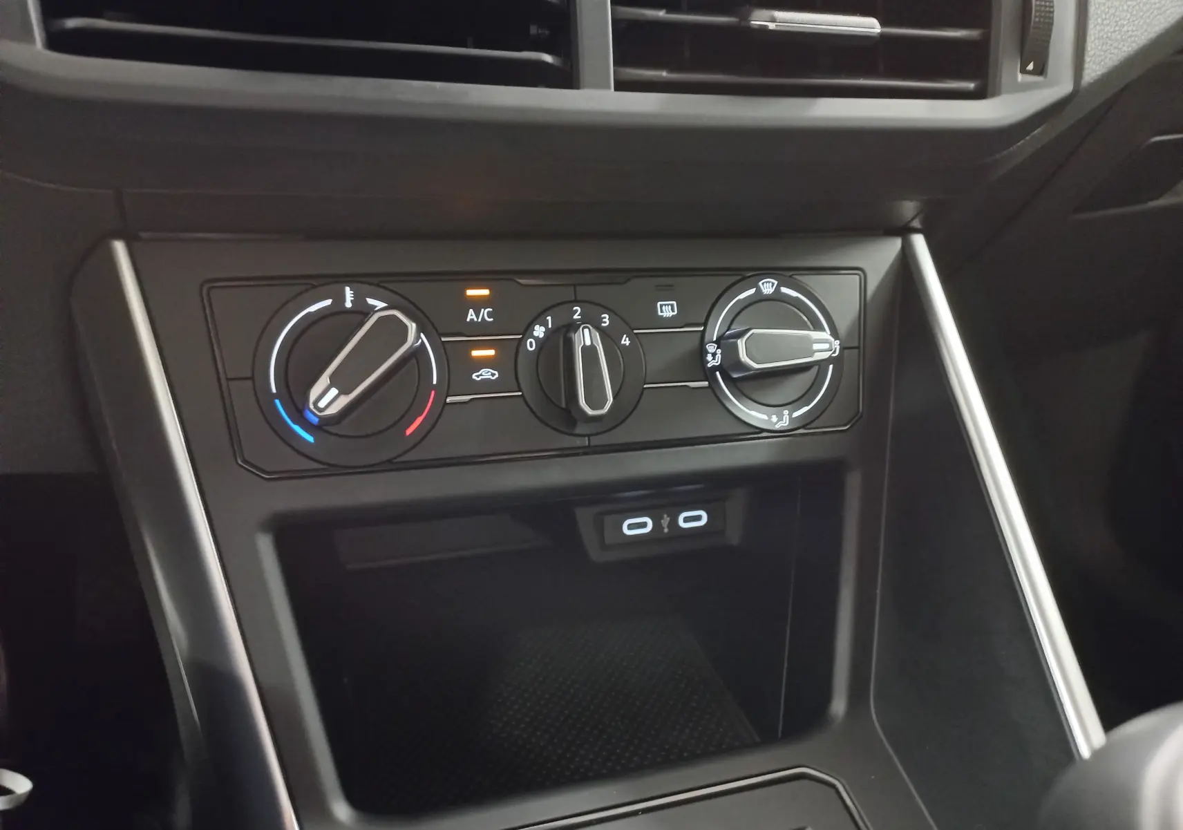 Gros plan sur les commandes de climatisation et les ports USB du tableau de bord d'une Volkswagen Polo 2024 couleur reflet d'argent.