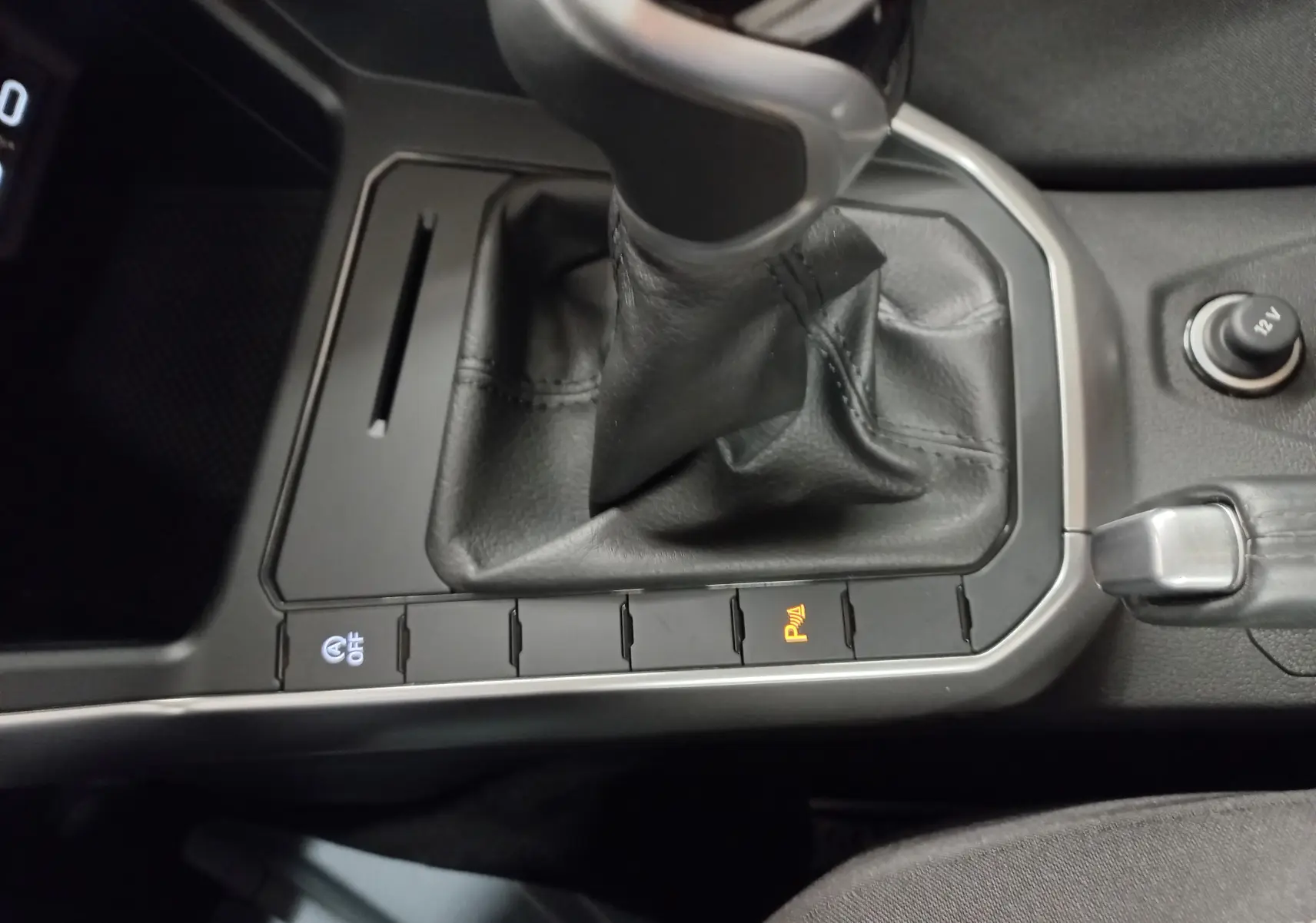 Gros plan sur la console centrale de la Volkswagen Polo 2024 avec levier de vitesse manuel et boutons de contrôle éclairés.