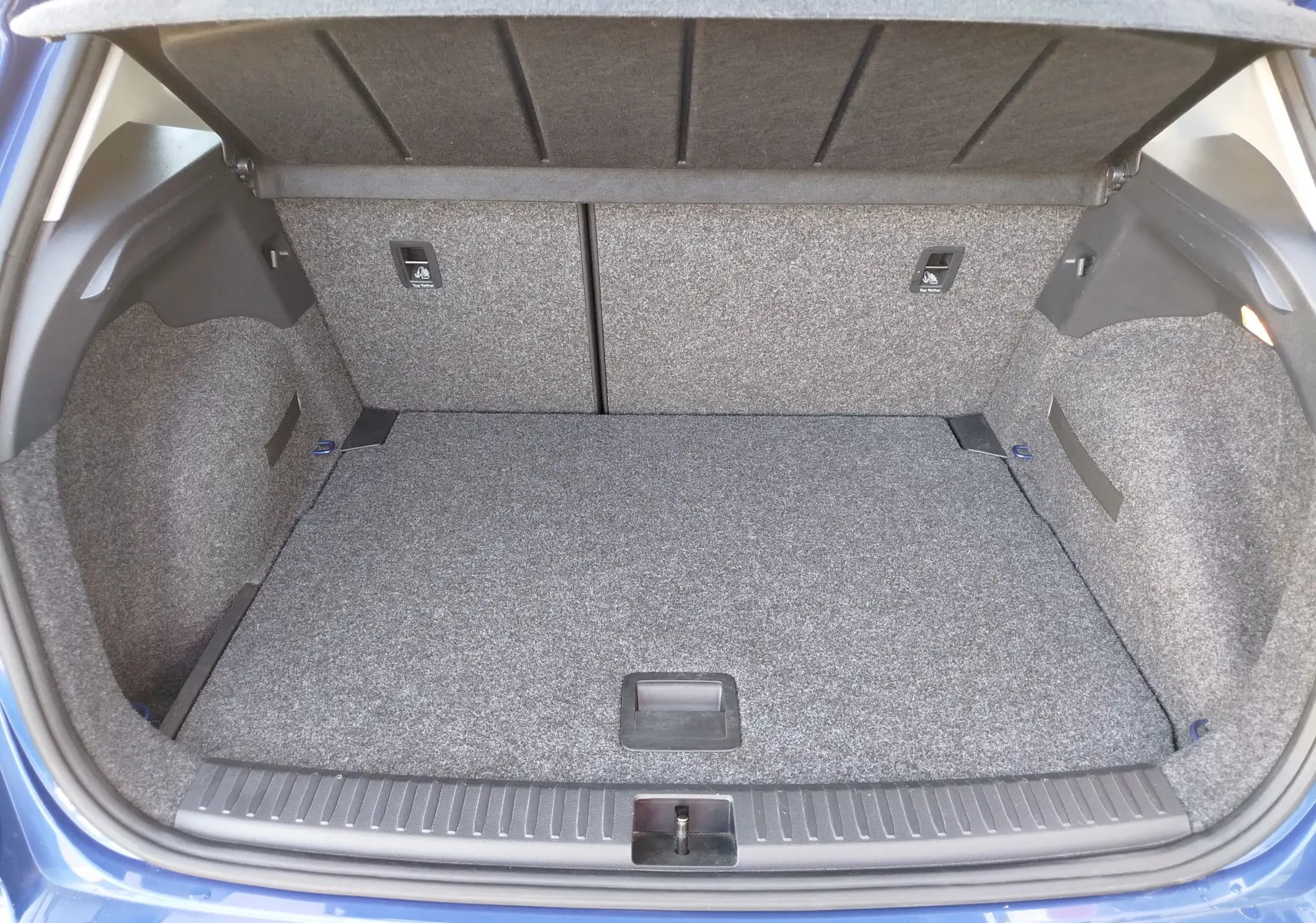 Coffre ouvert vu de l'arrière d'une SEAT Arona bleu électrique, montrant le volume et la finition intérieure grise.