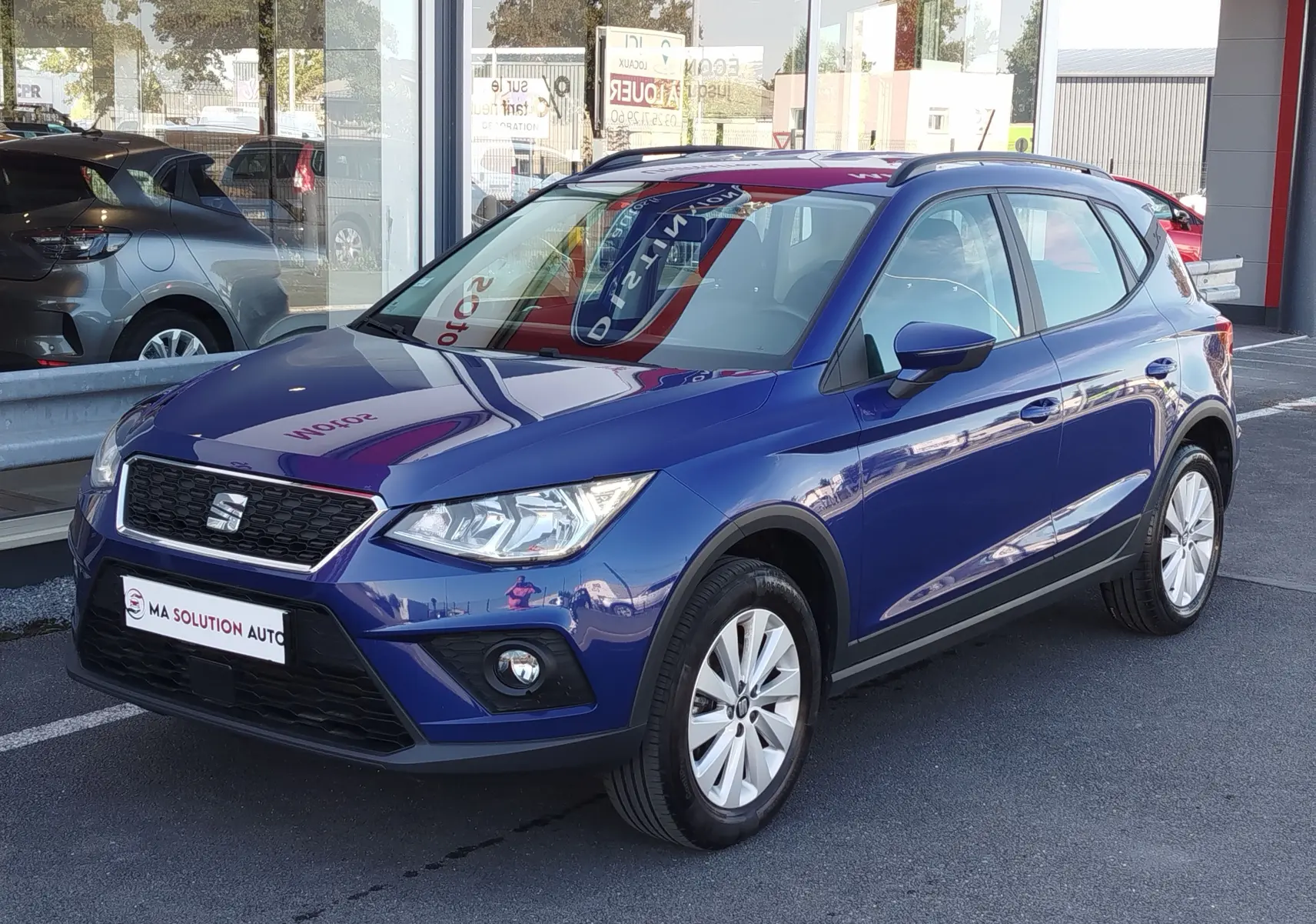 SEAT Arona bleu électrique en 3/4 avant droit, avec calandre noire et jantes argentées visibles en extérieur.