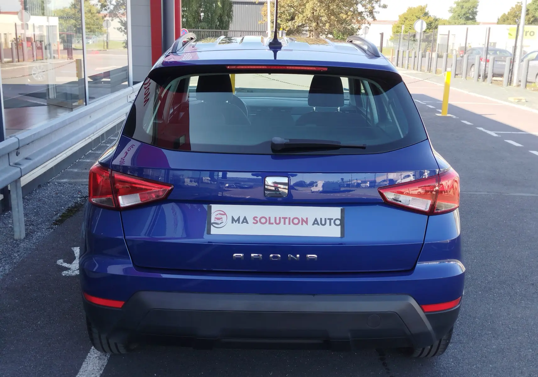 Vue arrière d'un SEAT Arona bleu électrique garé, mettant en valeur ses feux arrière anguleux et son hayon compact.