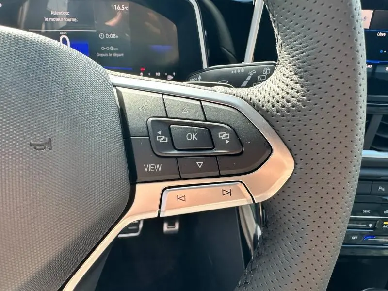 Gros plan sur les commandes multifonctions à droite du volant cuir perforé du Volkswagen T-Roc 2025, tableau de bord numérique en arrière-plan.