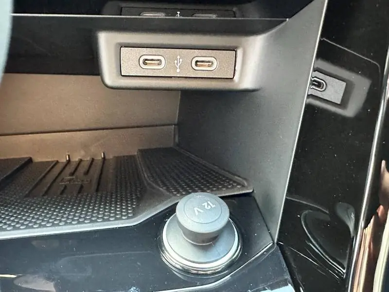 Gros plan sur la console centrale noire du Volkswagen T-Roc 2025, montrant prises USB-C et prise 12V.