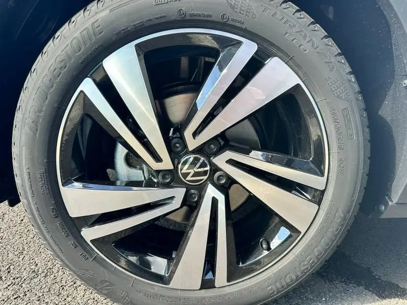 Gros plan sur la jante alu bicolore noire et argentée avec logo Volkswagen au centre du Volkswagen T-Roc 2025.