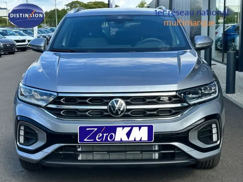 Vue frontale d'un Volkswagen T-Roc gris métallisé 2025 avec calandre R-Line et feux LED distinctifs.