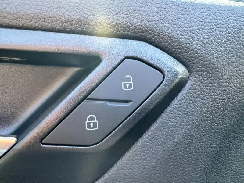 Gros plan sur les boutons de verrouillage et déverrouillage noirs sur la garniture intérieure en cuir noir du Volkswagen T-Roc 2025.