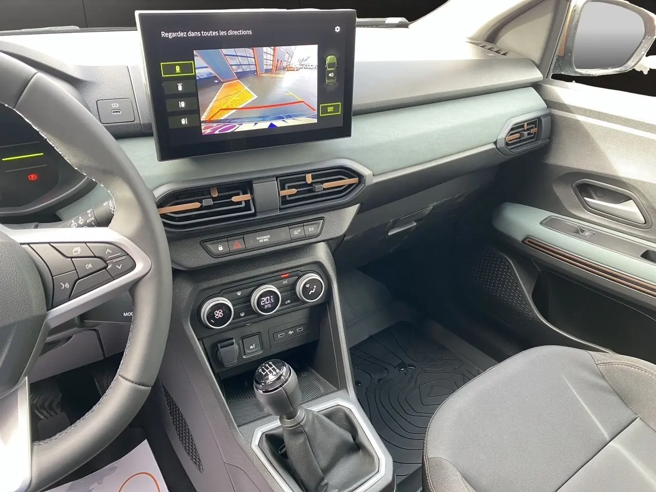 Vue intérieure côté conducteur de la Dacia Sandero Stepway 2026, montrant la console centrale avec écran tactile et levier de vitesse manuel.