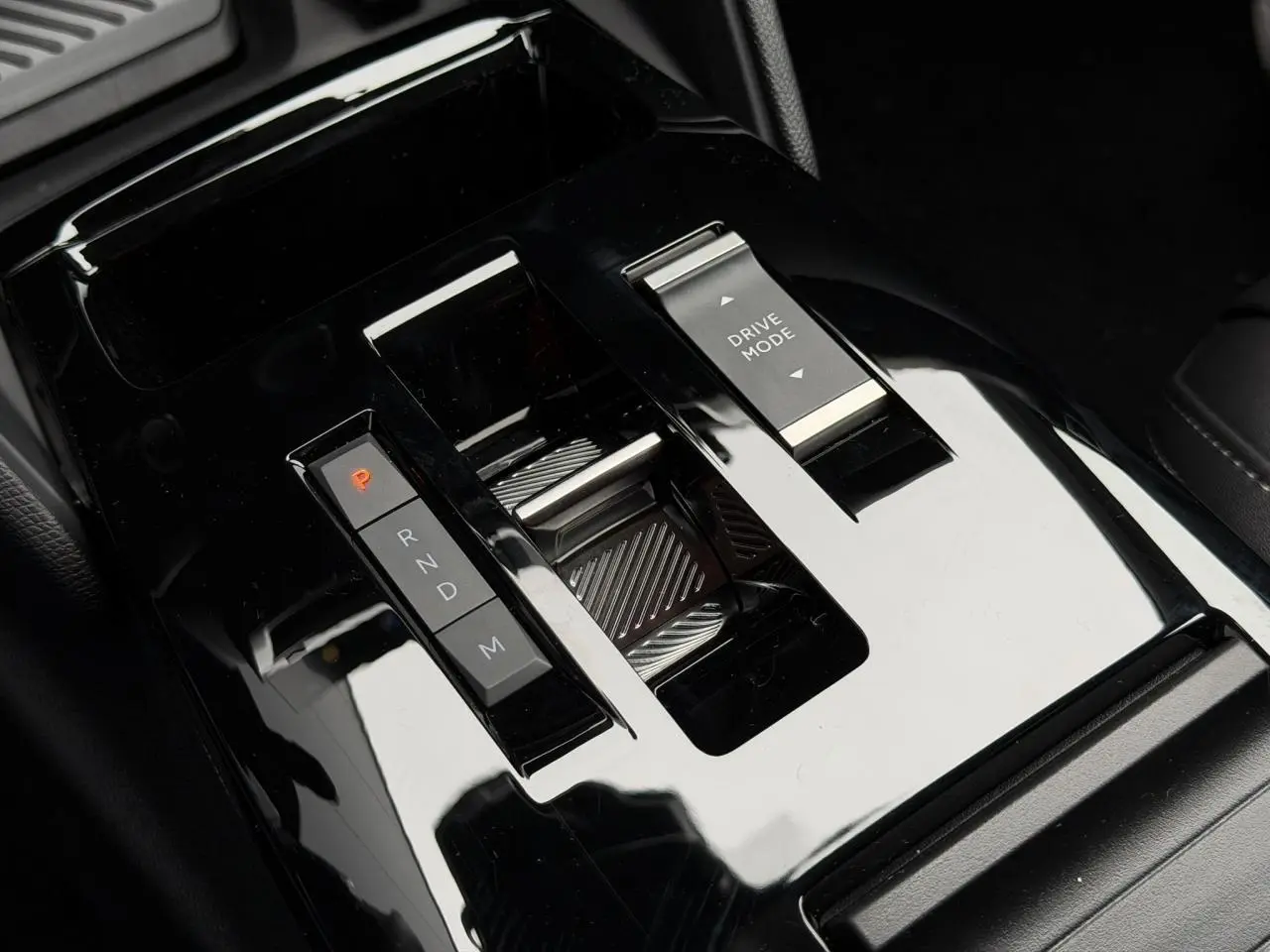 Gros plan sur la console centrale noire brillante de la Citroën C4 Hybrid 2025 avec sélecteur de vitesses et bouton Drive Mode.