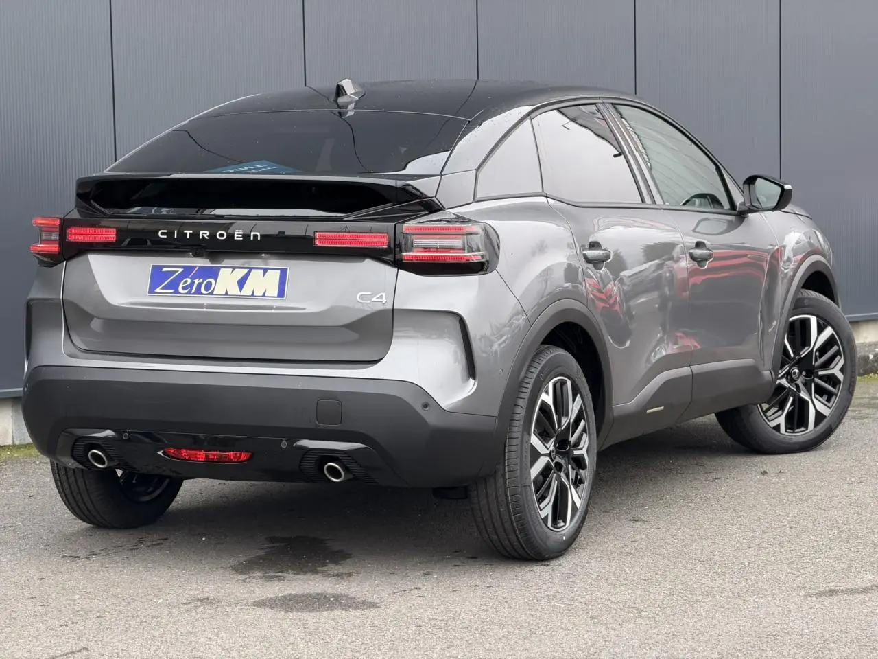 Vue 3/4 arrière droite d'une Citroën C4 gris Mercury avec toit bi-ton noir et jantes alliage 18 pouces.