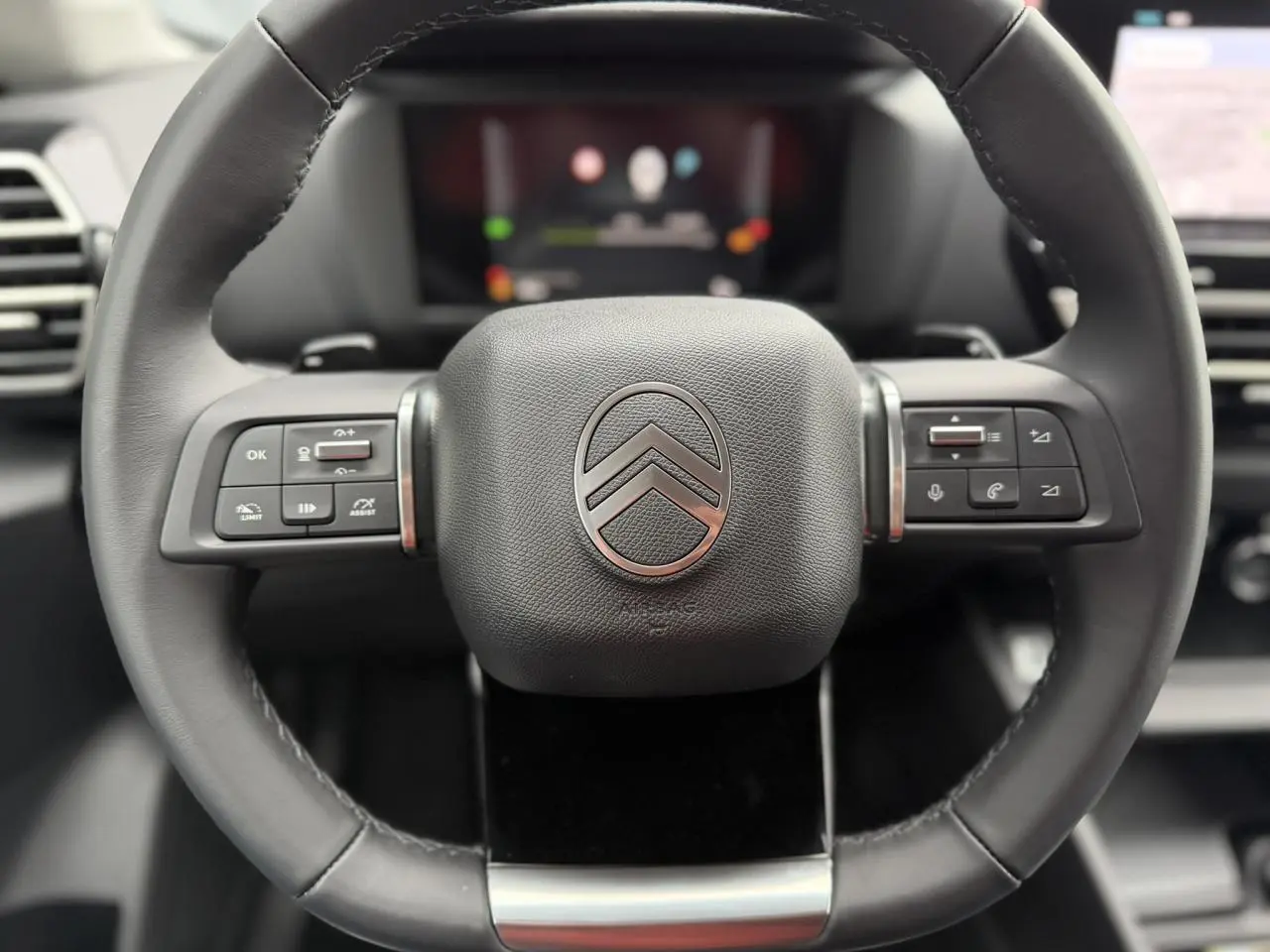 Gros plan sur le volant cuir noir du Citroën C4 2025 avec commandes intégrées et logo chromé au centre.