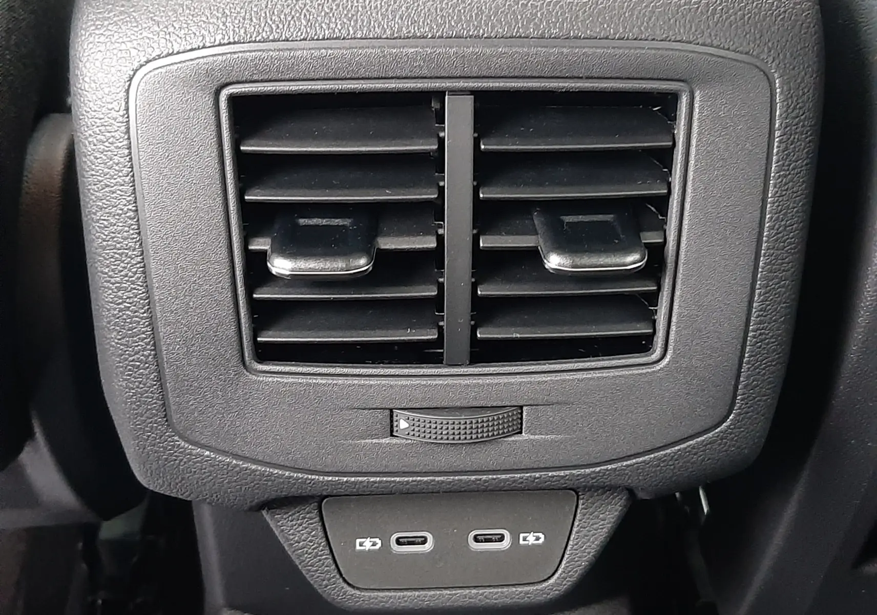 Détail des aérateurs arrière noirs avec deux ports USB-C sur la console centrale du Volkswagen T-Roc gris pyrite.