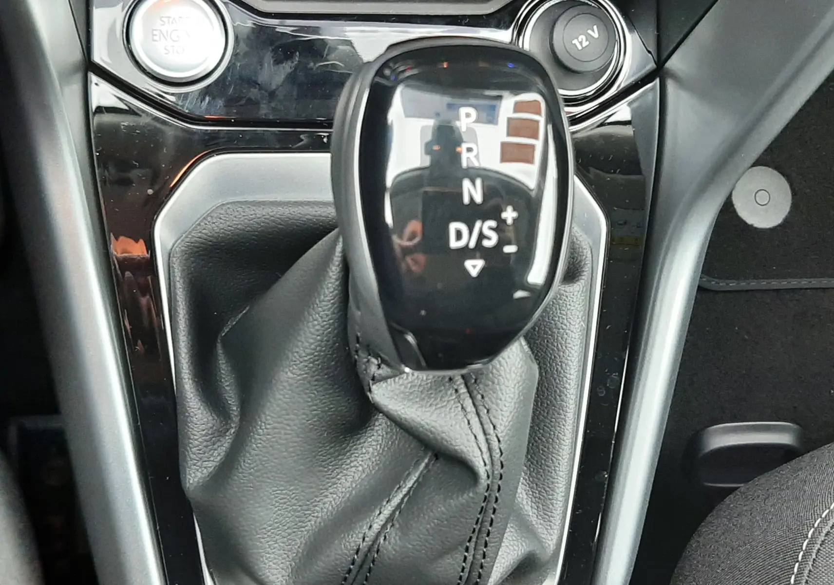 Gros plan sur le levier de vitesses automatique noir brillant du Volkswagen T-Roc 1.5 TSI 2025 avec habillage cuir gris.