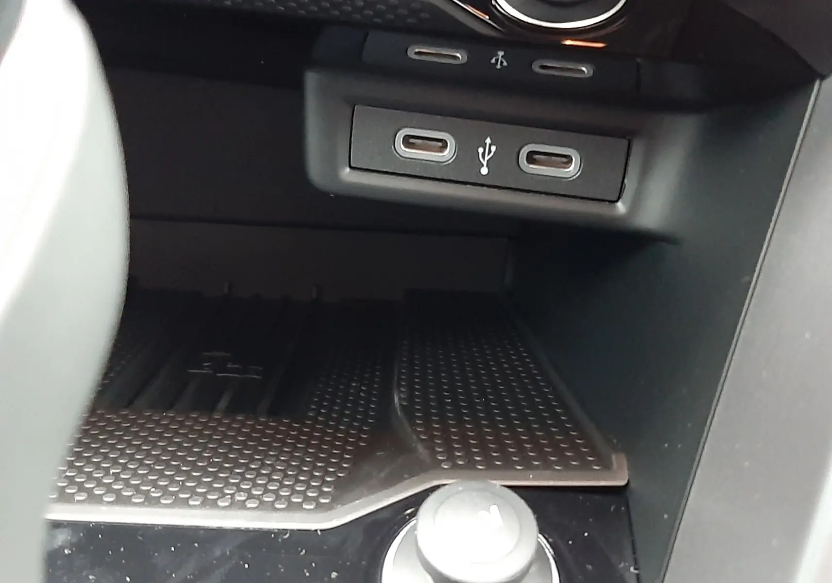 Vue rapprochée de la console centrale du Volkswagen T-Roc 2025, montrant les ports USB et le bouton de commande en noir brillant.