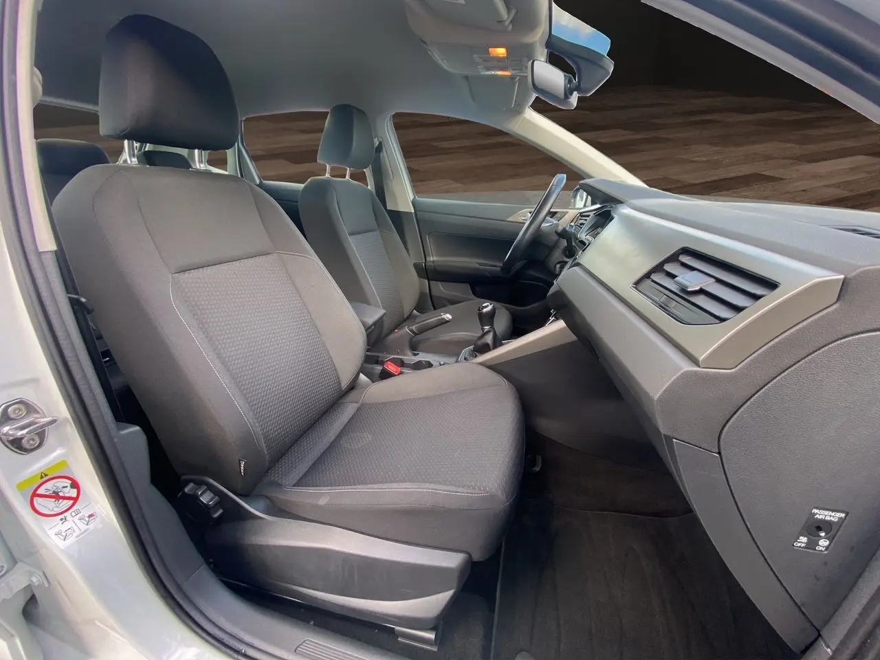 Vue intérieure côté droit de la Volkswagen Polo blanche, montrant les sièges avant en tissu noir et la console centrale.