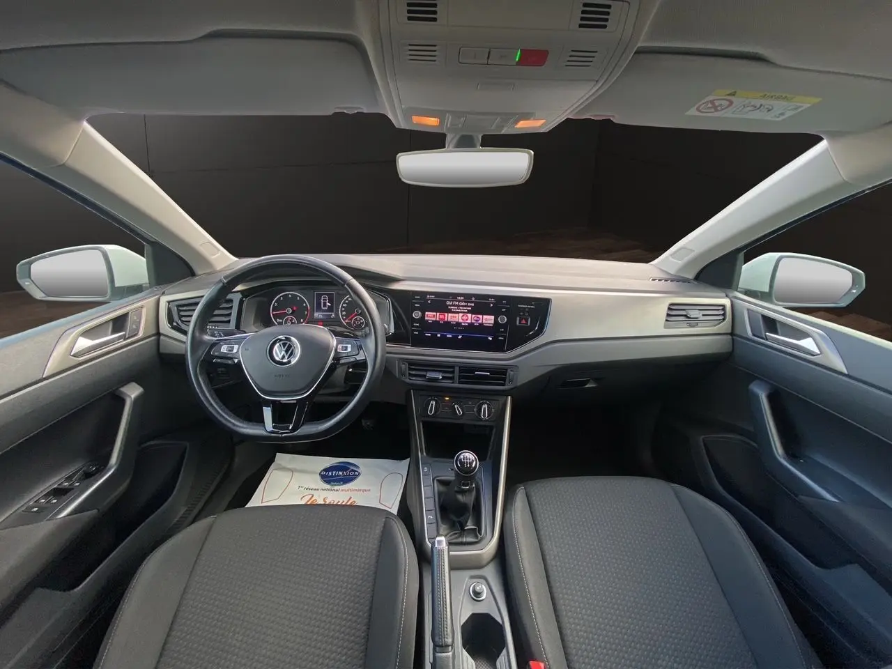 Vue intérieure avant de la Volkswagen Polo 1.0 80ch Lounge Business 2020, volant multifonction noir et console centrale avec boîte manuelle.