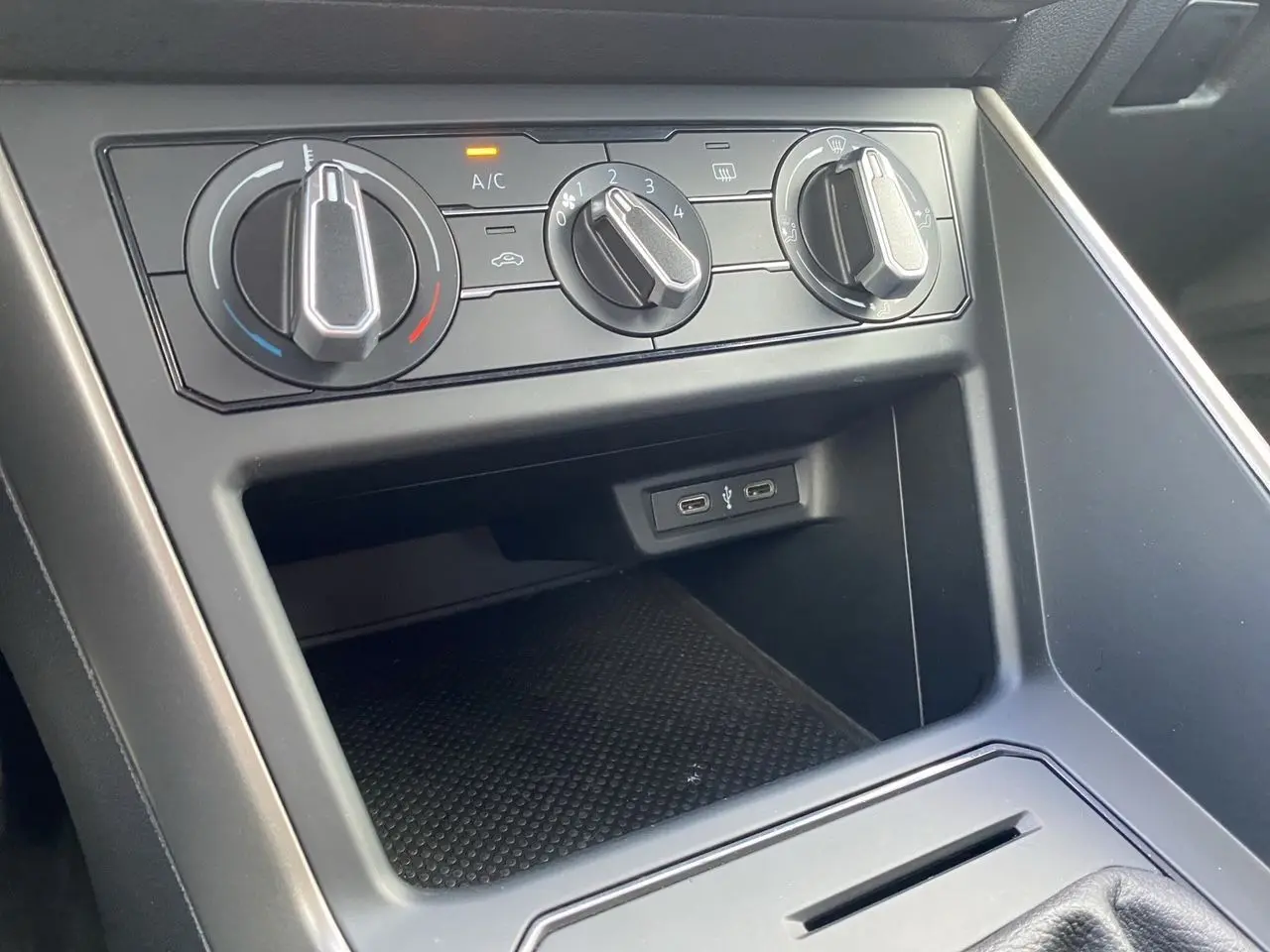 Gros plan sur la console centrale noire de la Volkswagen Polo 2020 avec commandes de climatisation et ports USB visibles.