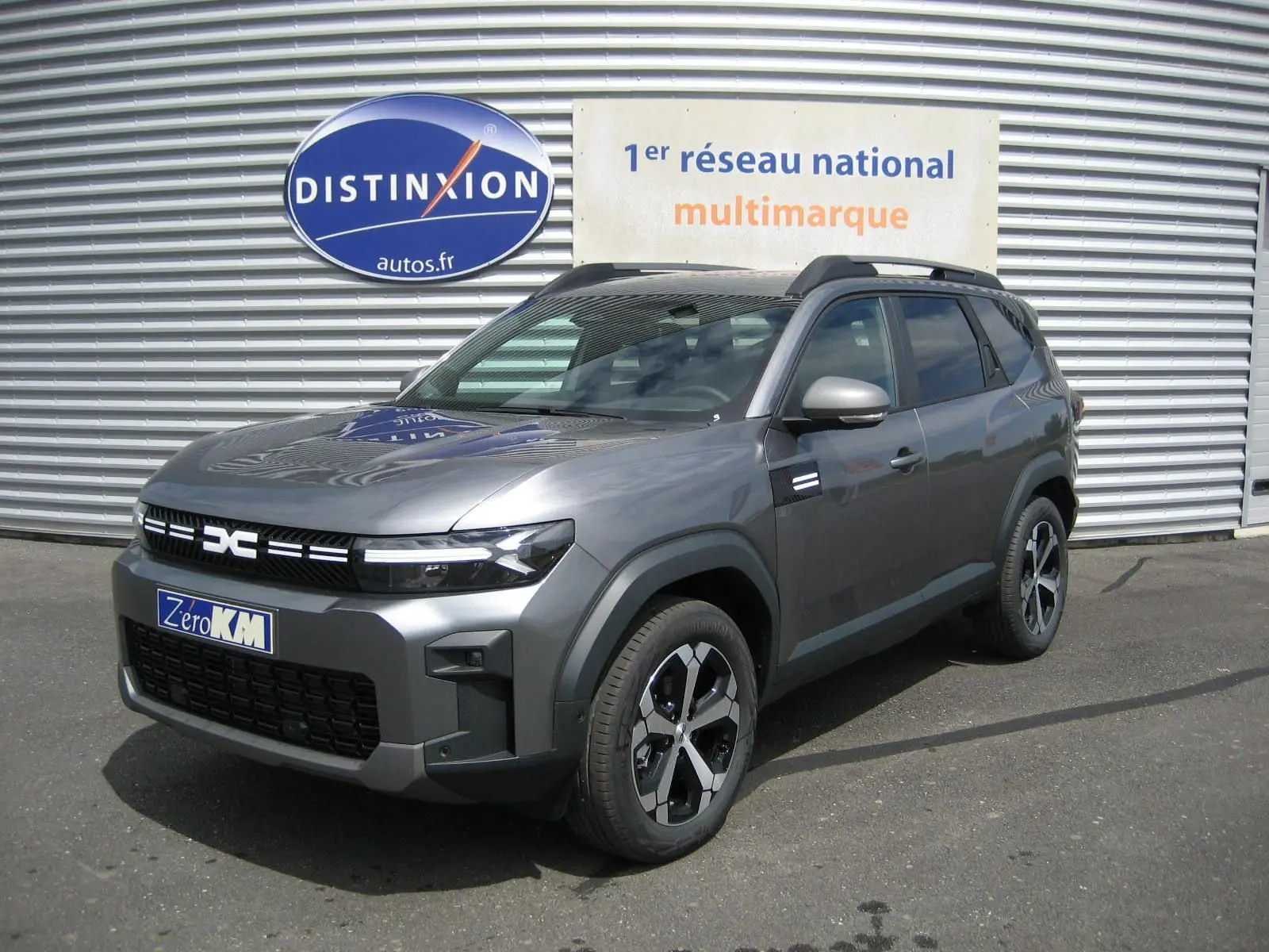 Dacia Bigster gris schiste en 3/4 avant droit, SUV hybride avec calandre noire et jantes modernes.