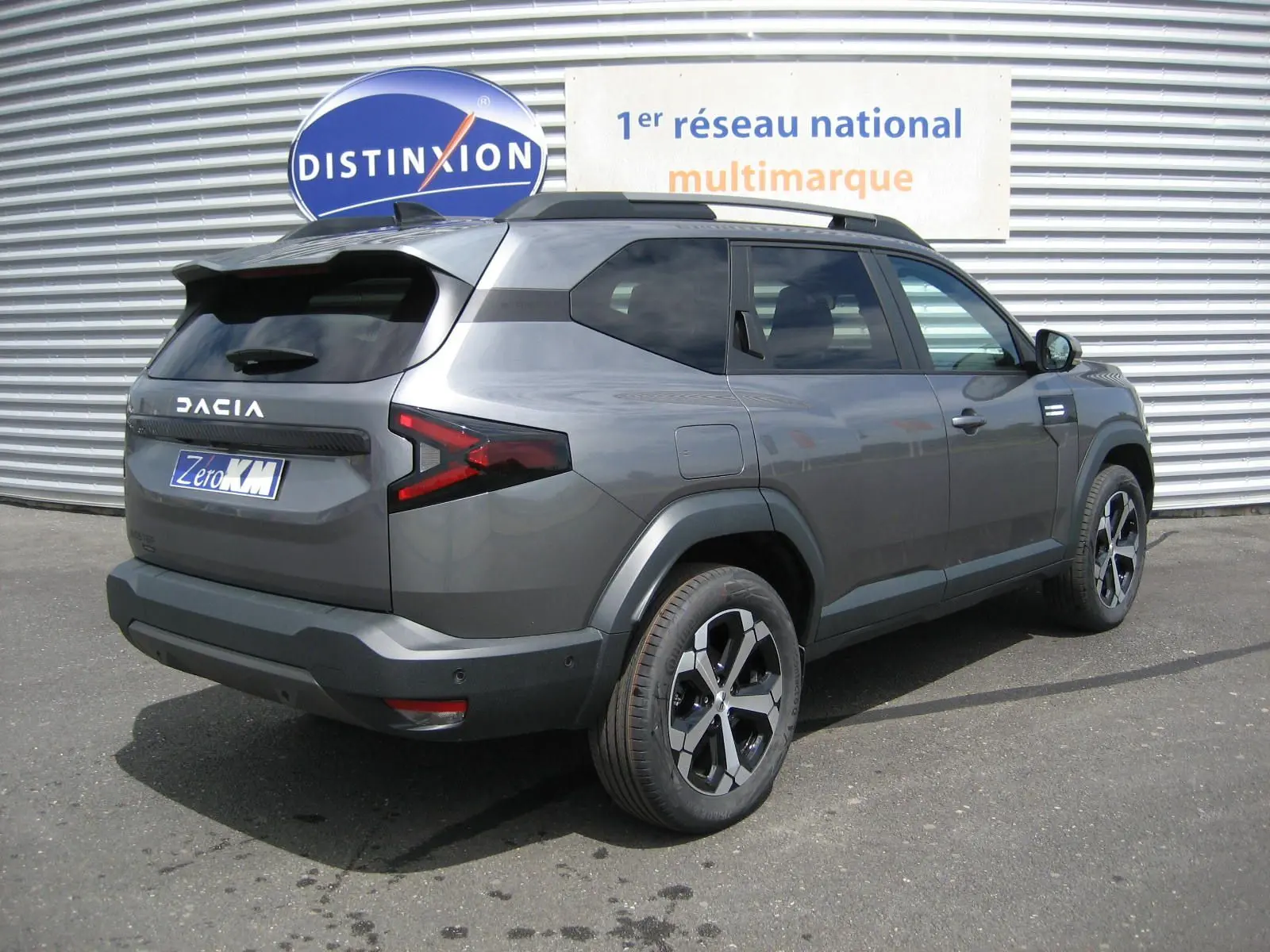 Vue 3/4 arrière droite du Dacia Bigster gris schiste avec ses feux arrière en forme de Z et jantes noires et argentées.