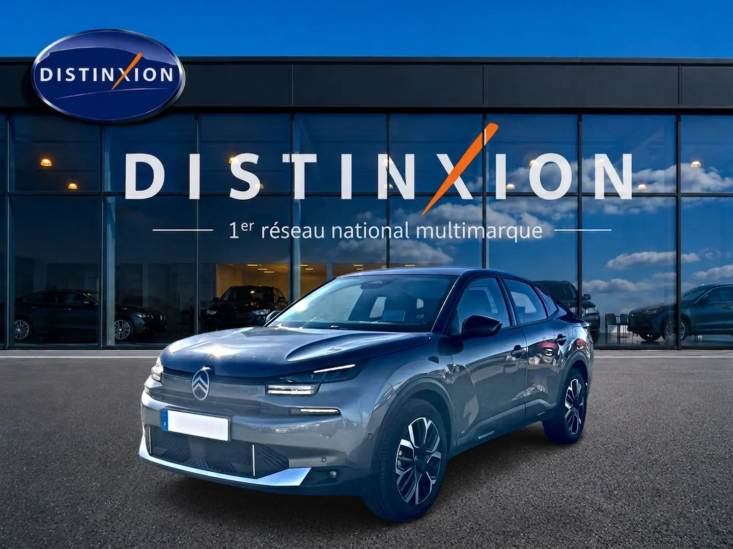 Vue 3/4 avant d'une Citroën C4 X gris mercure garée devant une vitrine avec logo Distinxion.