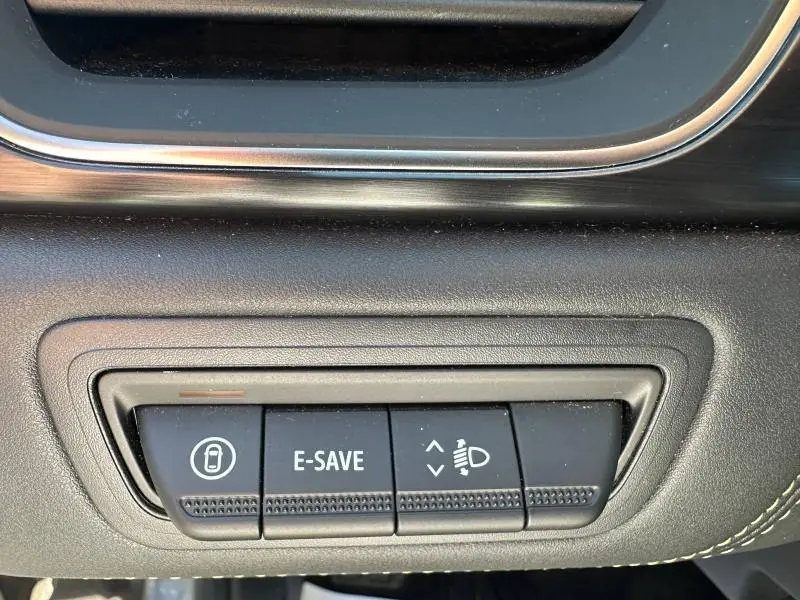 Gros plan sur les boutons de commande du tableau de bord du Renault Symbioz rouge, incluant fonction E-SAVE et réglage des phares.