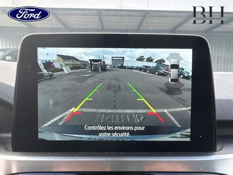Écran tactile intérieur montrant la caméra de recul avec lignes de guidage colorées sur un Ford Kuga gris Solar.